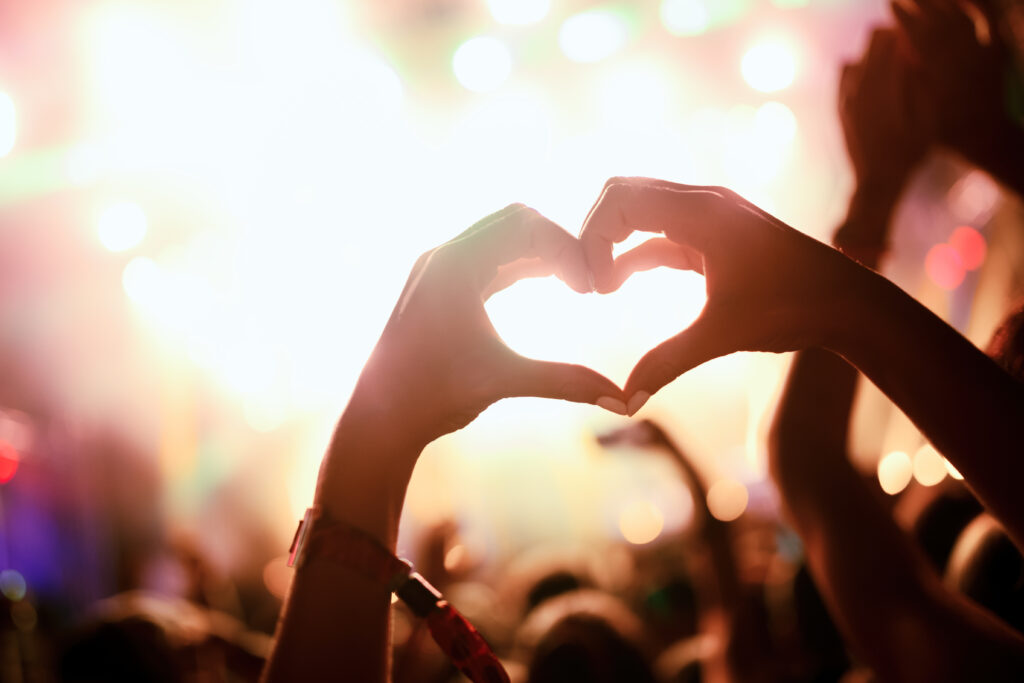 A festival-goer facing the stage forms a heart with her hands. We love festivals! A festival visitor facing the stage forms a heart with her hands. We love festivals!    Heliotextile